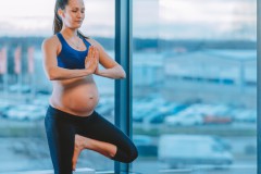 Young calm pregnant woman in tree pose during prenatal workout at gym or studio